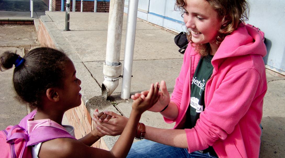 A Projects Abroad volunteer with children in South Africa plays a game during break time Childcare volunteer plays a game with a child during her volunteer work with children in South Africa